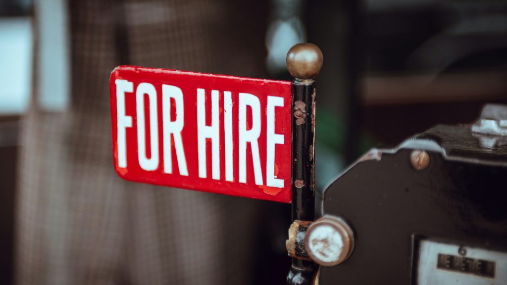 Close-up of a red "FOR HIRE" sign.
