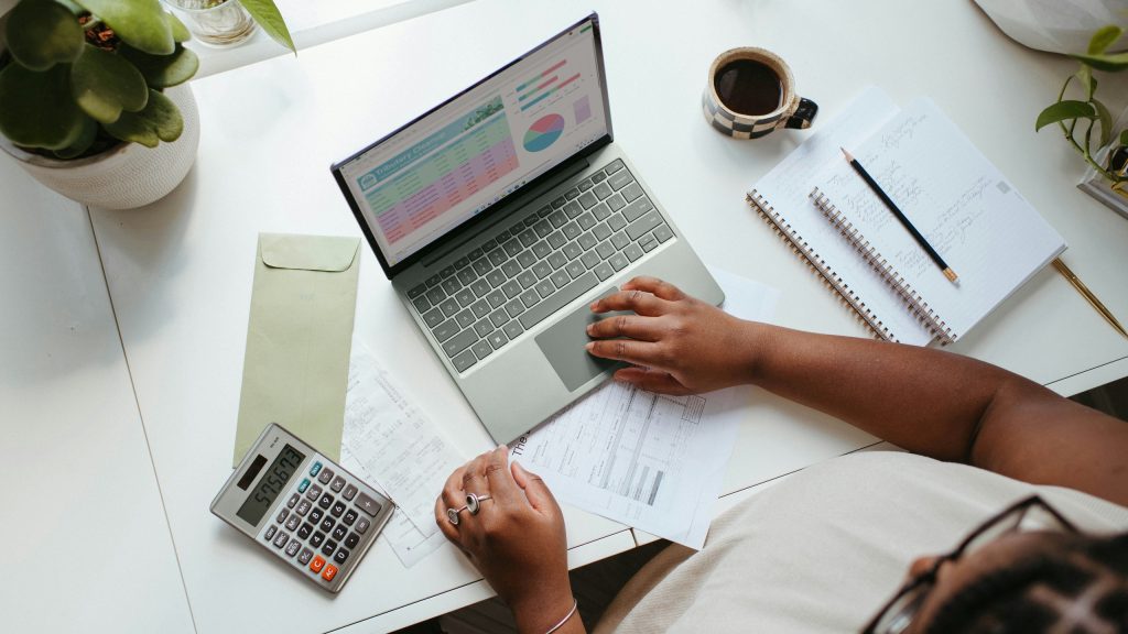 A person working on business financials with a laptop and calculator.