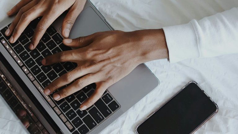 Close-up of hands typing on a laptop keyboard.