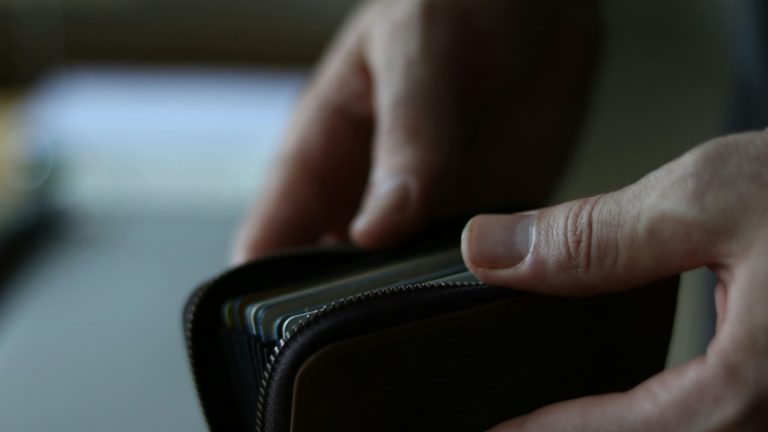 Close-up of hands opening a leather wallet.